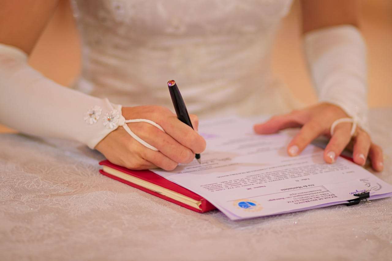 why-choose-us Close-up of a bride signing her wedding certificate at a ceremony.