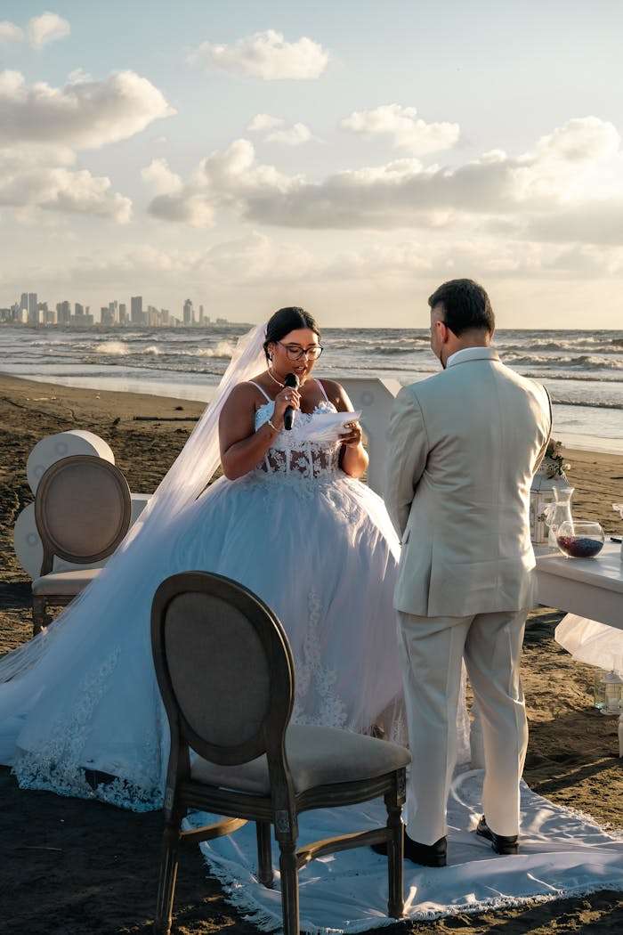 gallery-1 Romantic beachside wedding ceremony with a couple exchanging vows under the evening sky.
